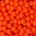 Pile of bright orange 8mm edible pearl beads for bulk dessert decoration.