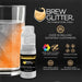 Orange color-changing edible beverage glitter in a mini spray pump next to a sparkling drink.