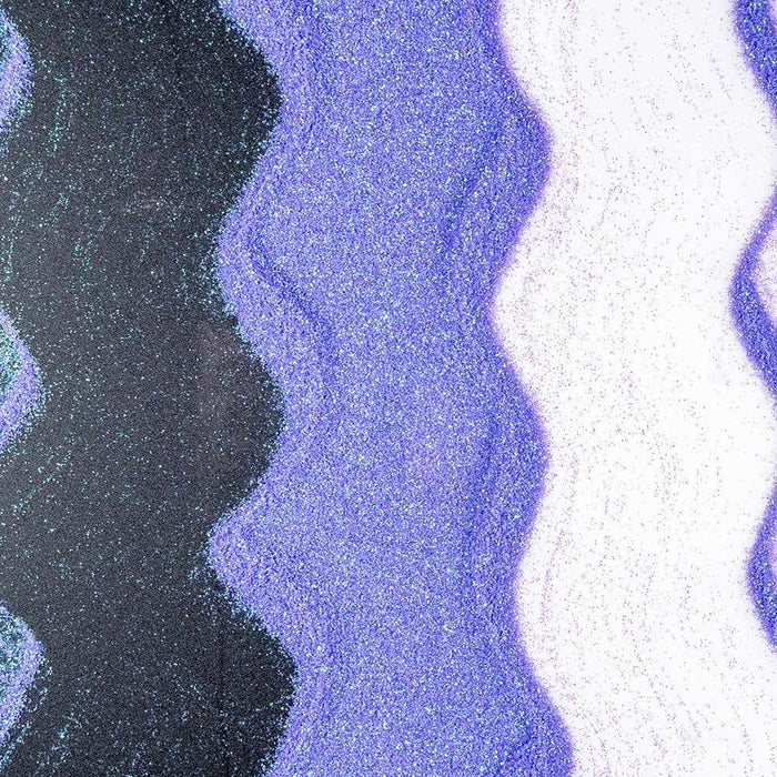 Wavy lines of pastel purple iridescent craft glitter on black and white surfaces.