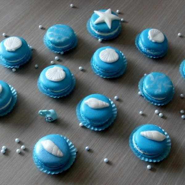 Patriot Blue Luster Dust macarons decorated with white edible seashells and stars, scattered with white pearls.