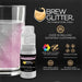 Pink color-changing Brew Glitter mini spray pump next to a glass of pink glittery drink.
