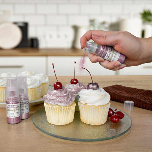 Three cupcakes being sprayed by a Pink Rose color Edible Glitter 4 gram pump. | bakell.com