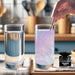 Hand stirring purple iridescent edible glitter into a glass of water next to a jar of Brew Glitter.
