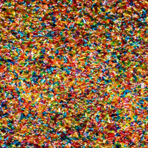 Close-up of vibrant rainbow edible shimmer flakes, a colorful mix of small, reflective pieces.