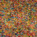 Close-up of vibrant rainbow edible shimmer flakes, a colorful mix of small, reflective pieces.
