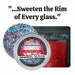 Red, white, and blue rimming sugar in a metal tin, next to a glass with a red drink and sugar-rimmed edge.