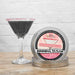 Rose gold pearl rimming sugar tin next to a martini glass with a black drink and pink sugar rim.