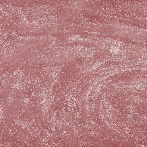 Swirling rose gold edible glitter particles creating a shimmering, metallic texture in a liquid drink.