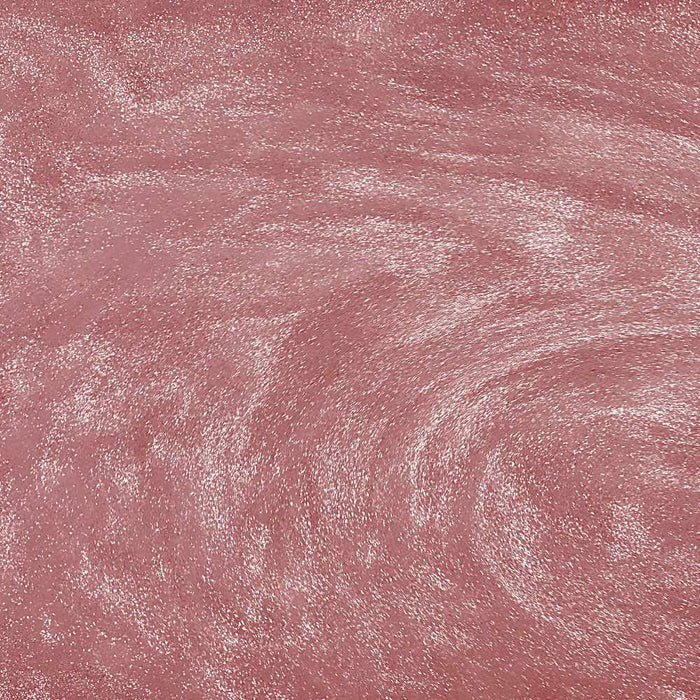 Swirling rose gold edible glitter particles creating a shimmering, metallic texture in a liquid drink.