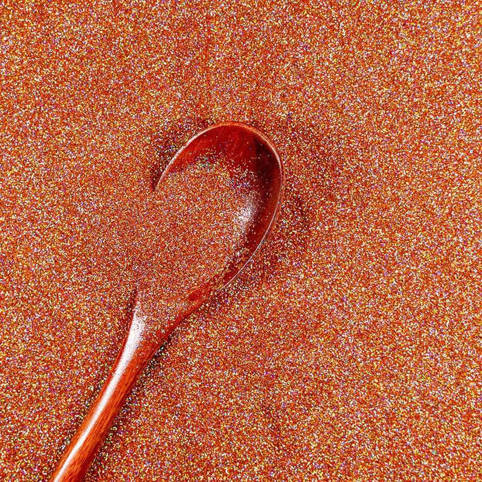 Rose gold ultrafine holographic craft glitter dust with a wooden spoon.