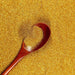 Royal Gold ultrafine aluminum craft glitter in a wooden spoon on a bed of shimmering gold dust.