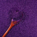 Royal Purple Ultrafine Metallic Craft Glitter Dazzler Dust with a wooden spoon scooping it.
