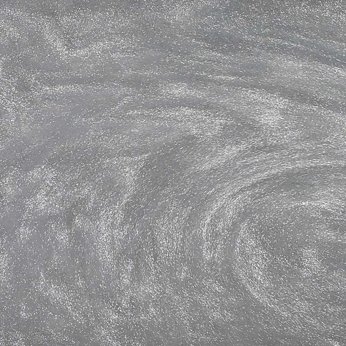 Swirling silver edible glitter dust creating a shimmering, metallic texture for cocktails and beverages.
