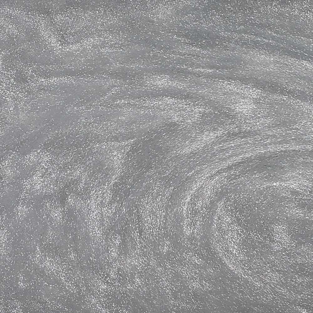 Swirling silver edible glitter particles creating a shimmering, metallic effect in a liquid beverage.