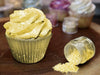 Sunflower Yellow Tinker Dust edible glitter on a frosted cupcake and spilled from a jar.