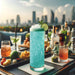 Tall glass of sparkling teal color-changing brew glitter cocktail with lime and mint, on a rooftop bar.