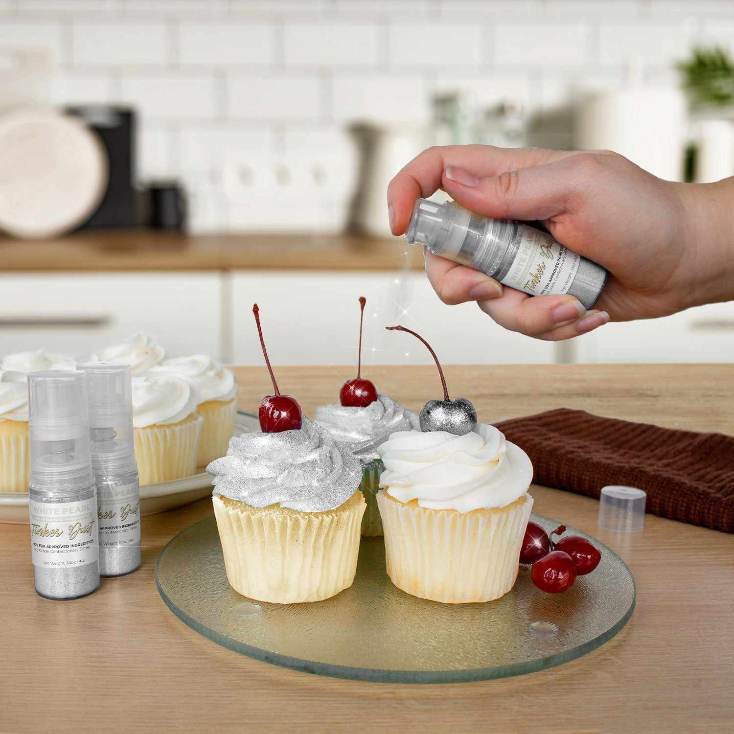 Three cupcakes being sprayed by a White color Edible Glitter 4 gram pump. | bakell.com