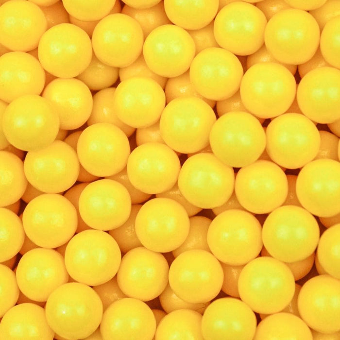 Close-up of numerous bright yellow 8mm edible pearl beads, perfect for dessert decoration.