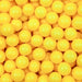 Close-up of numerous bright yellow 8mm edible pearl beads, perfect for dessert decoration.