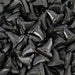 Pile of shiny black witch hat shaped edible sprinkles.