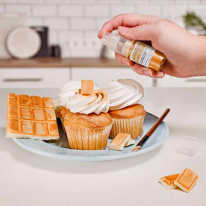 Three cupcakes and a wafer being sprayed by an Orange color Luster Dust 4 gram pump. | bakell.com
