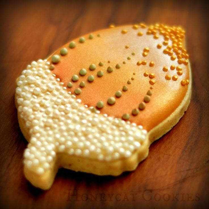 Classic Orange Luster Dust on an acorn-shaped cookie with white and gold pearl sprinkles.