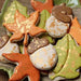 Assorted fall leaf and acorn cookies with orange, green, and white icing, speckled with gold luster dust.