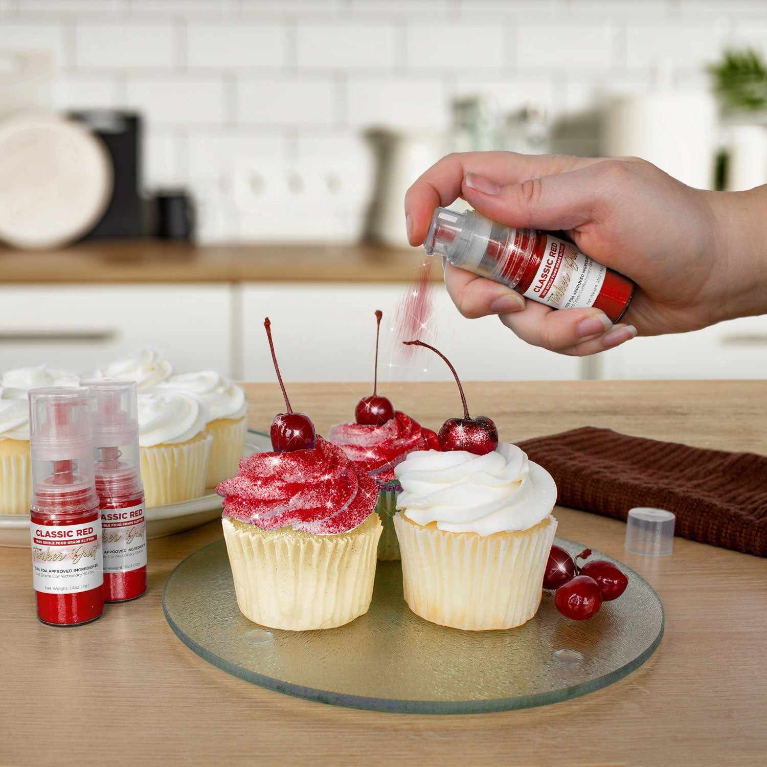 Three cupcakes being sprayed by a Classic Red colored Edible Glitter 4 gram pump. | bakell.com