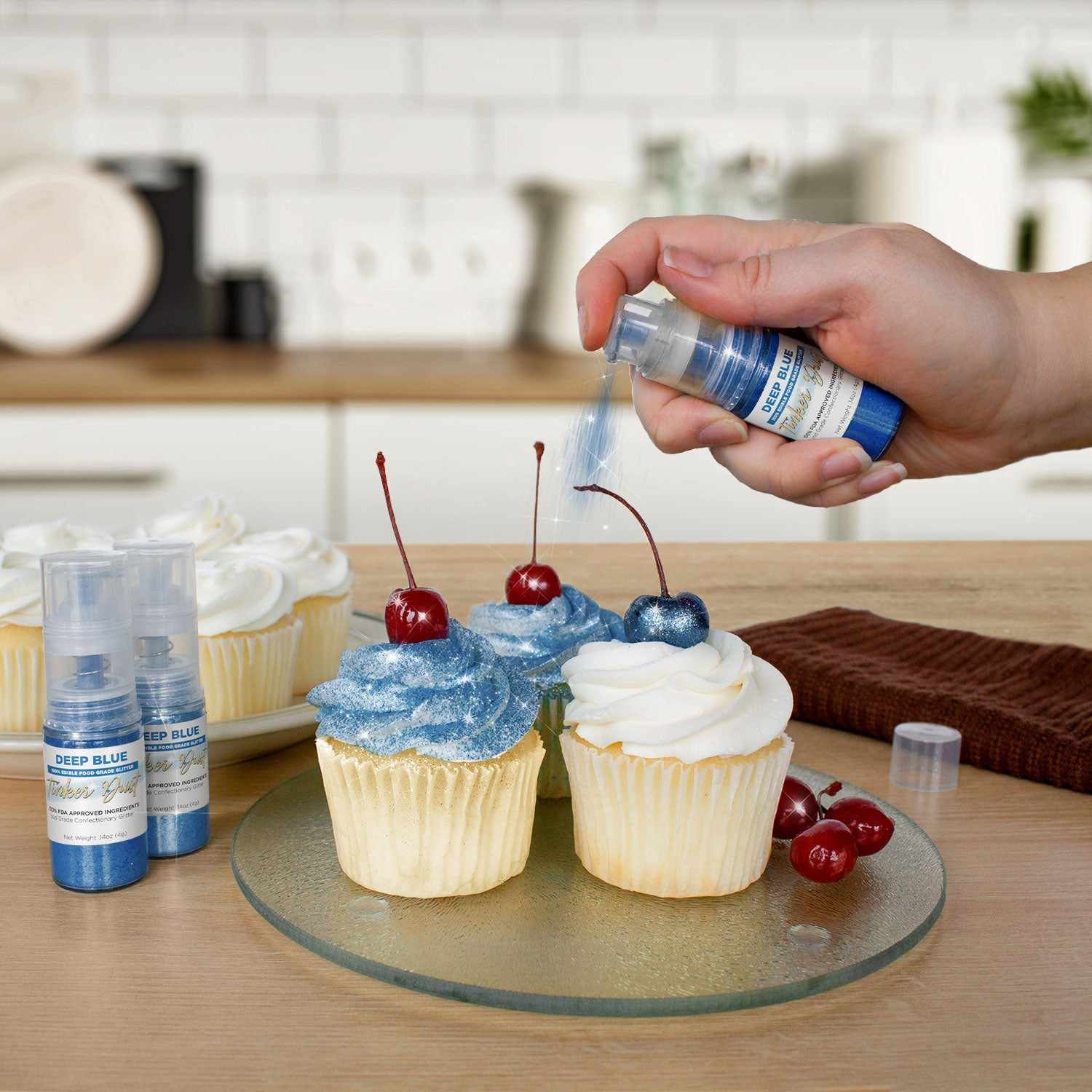 Three cupcakes being sprayed by a Deep Blue color Edible Glitter 4 gram pump. | bakell.com