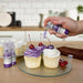 Three cupcakes being sprayed by a Deep Purple color Edible Glitter 4 gram pump. | bakell.com