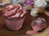 Red Tinker Dust edible glitter on a frosted cupcake and spilling from a small jar.