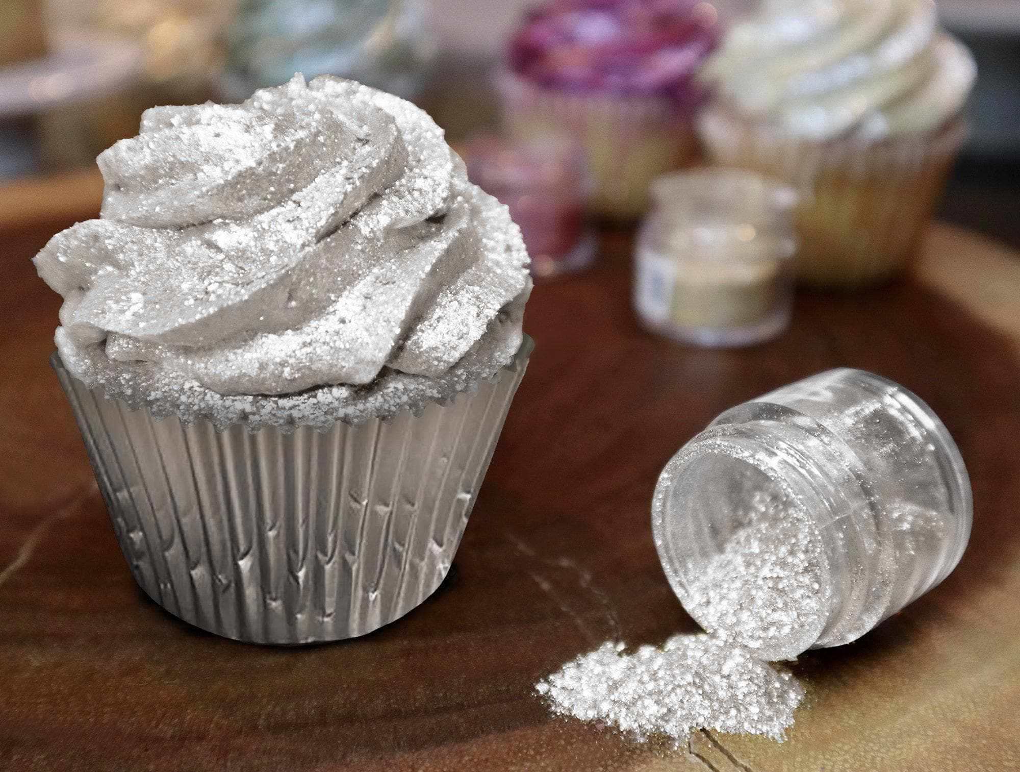 Ivory Tinker Dust edible glitter sprinkled on a frosted cupcake and spilling from a jar.