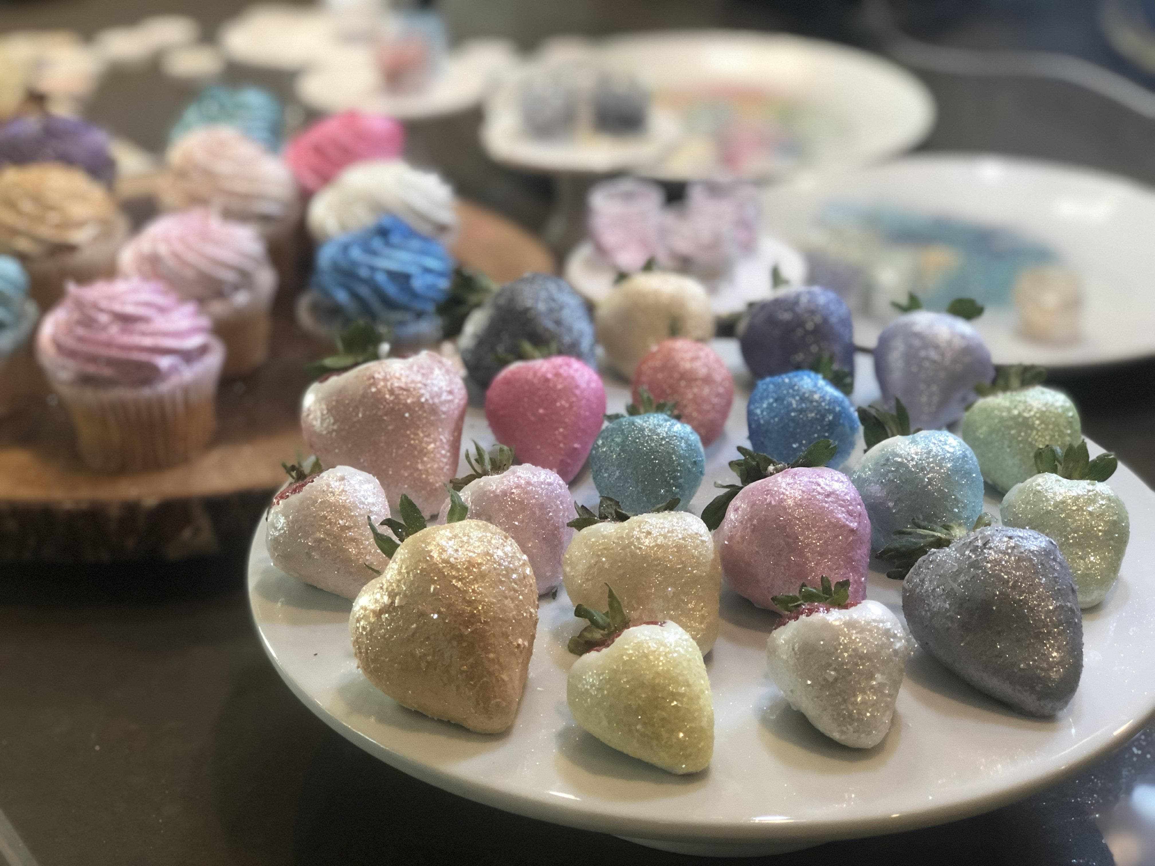 Assortment of Tinker Dust® glitter-covered strawberries and cupcakes in various pastel colors.