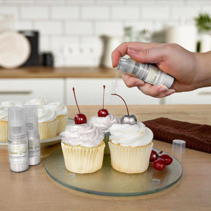 Three cupcakes being sprayed by an Ivory color Edible Glitter 4 gram pump. | bakell.com