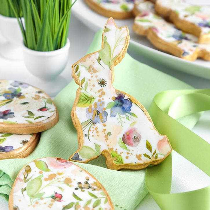 Leaf green luster dust on a white bunny cookie with floral designs and gold speckles.