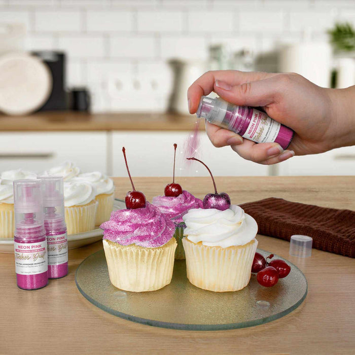 Three cupcakes being sprayed by a Neon Pink color Edible Glitter 4 gram pump. | bakell.com