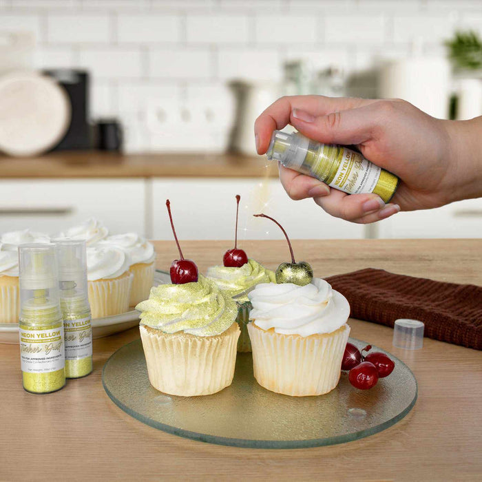 Three cupcakes being sprayed by a Neon Yellow color Edible Glitter 4 gram pump. | bakell.com