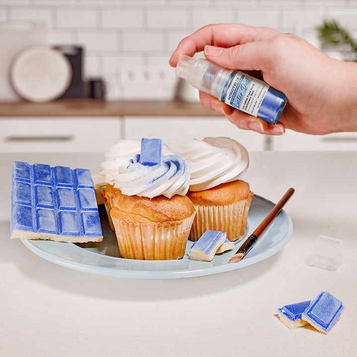 Three cupcakes and a wafer being sprayed by a Blue color Luster Dust 4 gram pump. | bakell.com