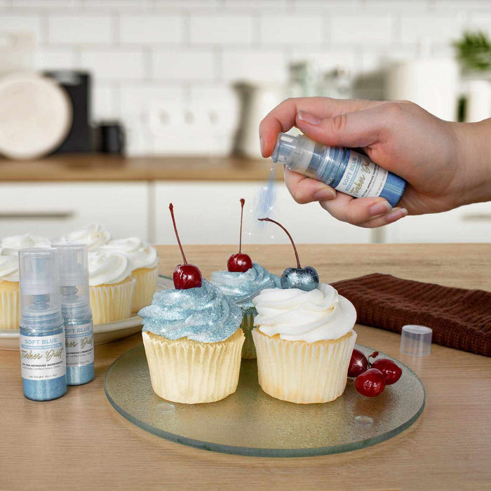 Three cupcakes being sprayed by a Soft Blue color Edible Glitter 4 gram pump. | bakell.com
