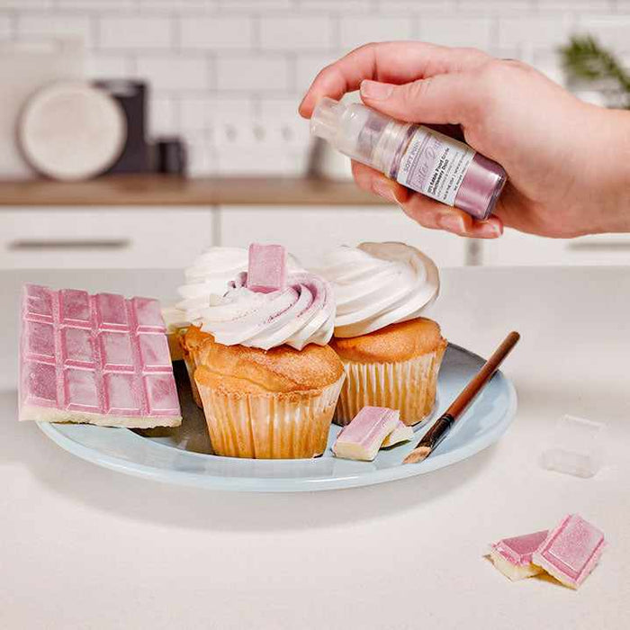 Three cupcakes and a wafer being sprayed by a Pink color Luster Dust 4 gram pump. | bakell.com