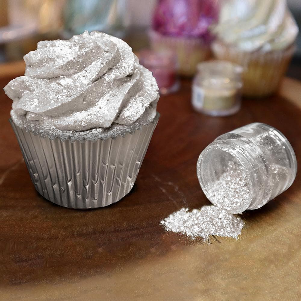 Silver Tinker Dust edible glitter sprinkled on a cupcake with a clear jar spilling more glitter.