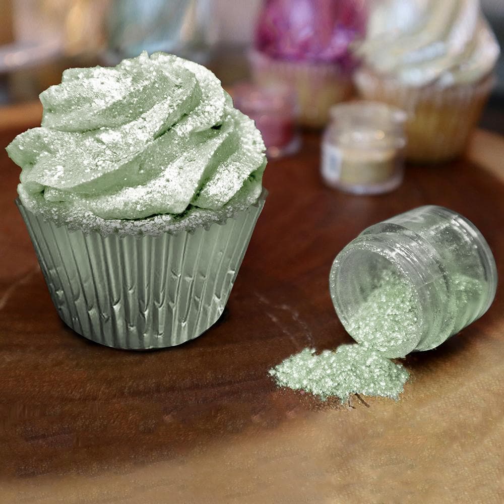 Green Tinker Dust edible glitter sprinkled on a frosted cupcake next to an open jar.