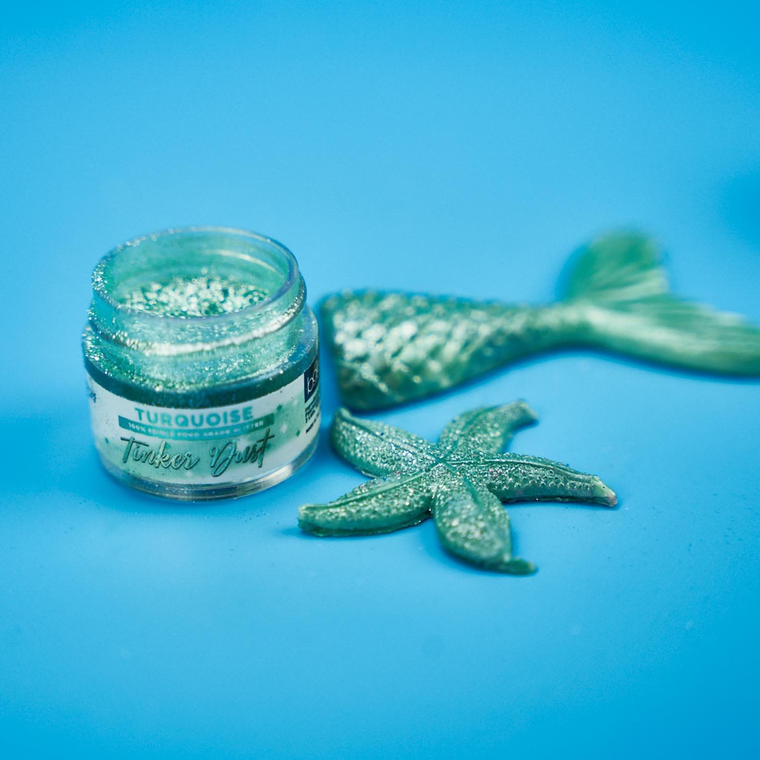 Turquoise Tinker Dust edible glitter jar with matching mermaid tail and starfish decorations.