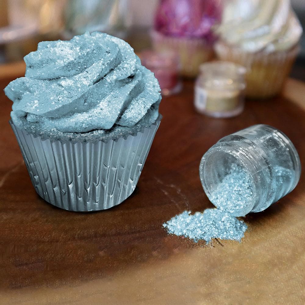 Light blue glitter Tinker Dust sprinkled on a frosted cupcake, with a spilled jar of the edible glitter.