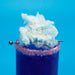 Purple drink with a pink sugar rim, topped with light blue cotton candy and colorful sprinkles.